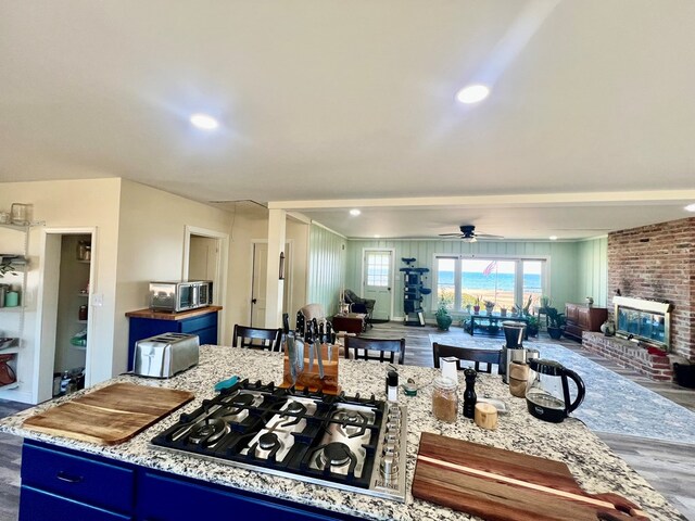 kitchen featuring ceiling fan, a center island, black gas cooktop, blue cabinets, and hardwood / wood-style flooring