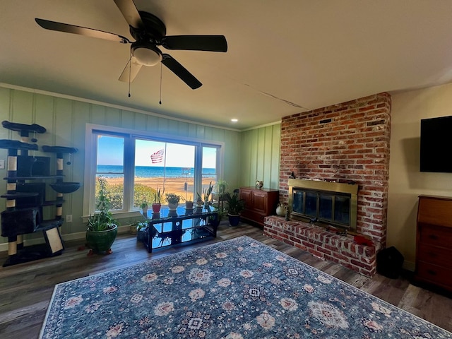 living area featuring a brick fireplace, crown molding, baseboards, and wood finished floors