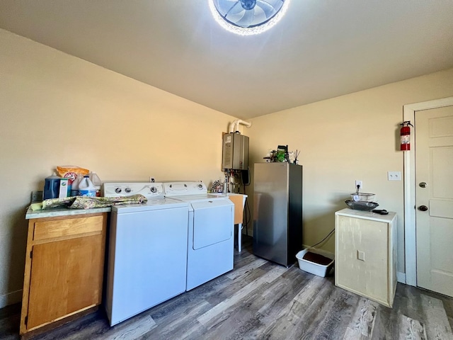 clothes washing area featuring dark wood-style flooring, washing machine and clothes dryer, water heater, cabinet space, and a sink