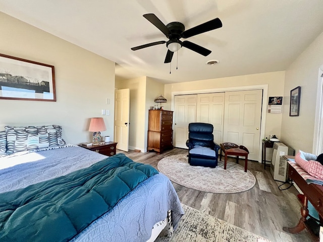 bedroom with ceiling fan, a closet, visible vents, and wood finished floors