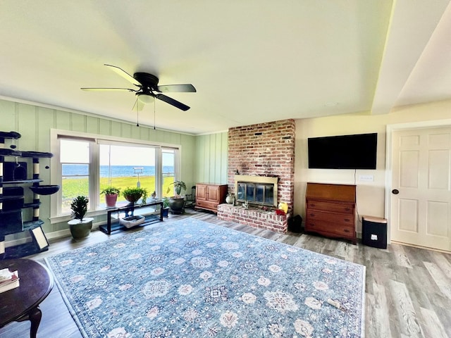 living room featuring ceiling fan, light hardwood / wood-style floors, and a fireplace