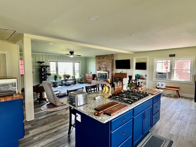 kitchen with open floor plan, stainless steel gas stovetop, blue cabinetry, and wood finished floors