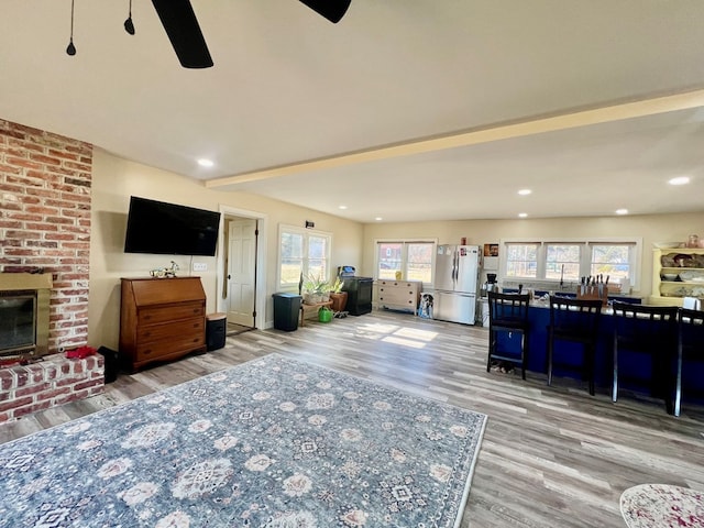 living area featuring ceiling fan, a brick fireplace, wood finished floors, and recessed lighting