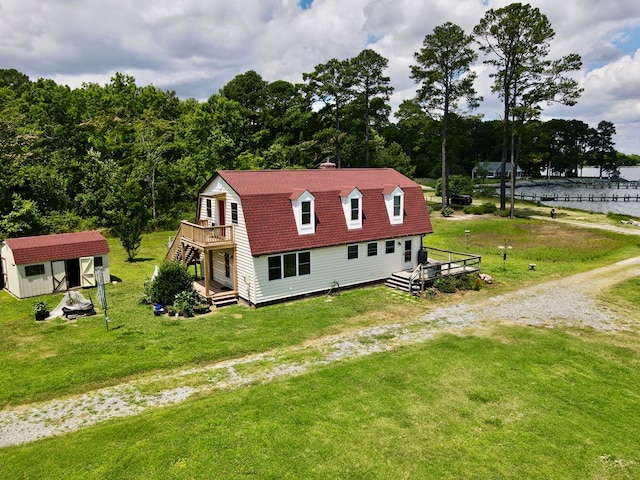 view of side of property with a lawn, a storage unit, and a deck with water view