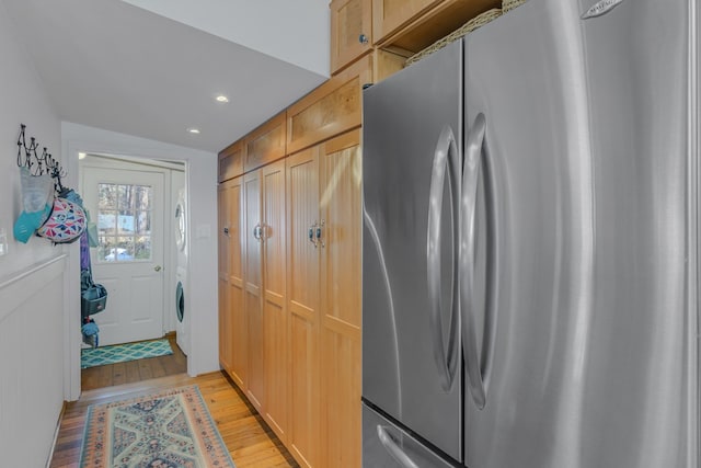 kitchen featuring freestanding refrigerator, light wood-type flooring, stacked washing maching and dryer, light brown cabinets, and recessed lighting