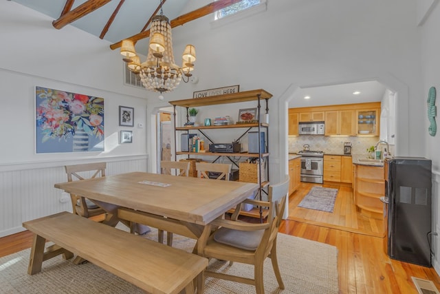 dining room with visible vents, wainscoting, a high ceiling, light wood-style floors, and a chandelier