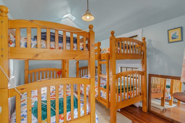 bedroom with lofted ceiling and wood finished floors