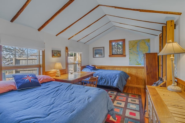 bedroom with a wainscoted wall, multiple windows, wood finished floors, and wood walls