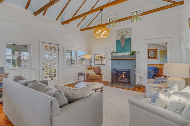 living room with a wainscoted wall, plenty of natural light, beamed ceiling, and a fireplace