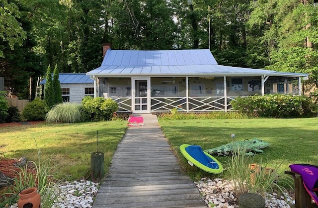 view of front of house featuring a standing seam roof, a chimney, metal roof, and a front yard