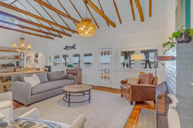 living area with a chandelier, high vaulted ceiling, light wood-type flooring, and a healthy amount of sunlight