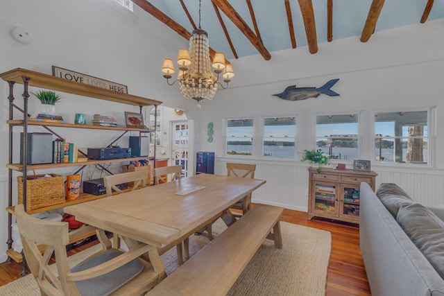 dining space with a wealth of natural light, a wainscoted wall, beamed ceiling, and wood finished floors