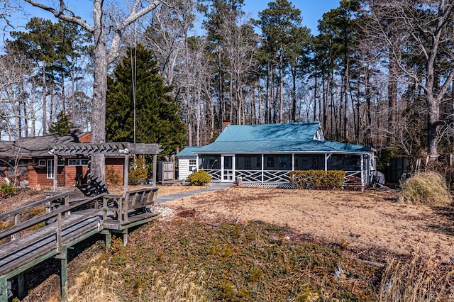 back of house featuring a sunroom, metal roof, and a pergola