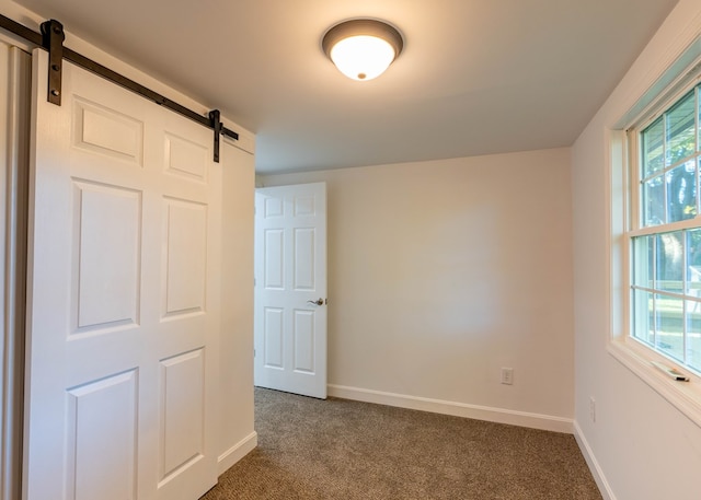 empty room with carpet, a barn door, and a wealth of natural light