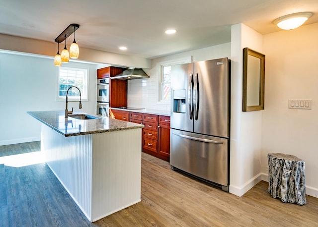 kitchen featuring sink, wall chimney exhaust hood, tasteful backsplash, stone countertops, and appliances with stainless steel finishes