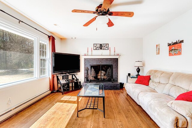 living room with a fireplace, ceiling fan, and light wood-type flooring