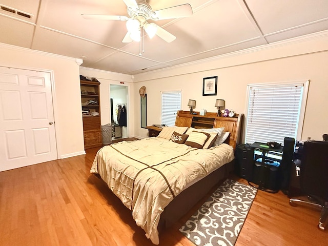 bedroom with hardwood / wood-style flooring, ceiling fan, and crown molding