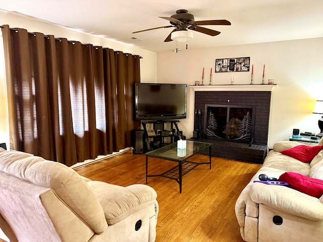 living room with ceiling fan, a fireplace, and light hardwood / wood-style floors