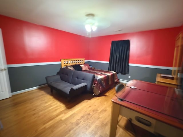 bedroom featuring hardwood / wood-style floors and a baseboard heating unit