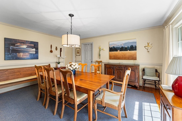 dining space with crown molding and a wainscoted wall