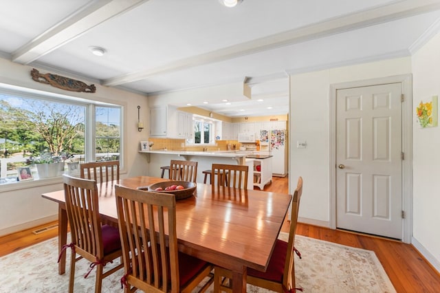 dining room with crown molding, light wood-style flooring, baseboards, beamed ceiling, and visible vents