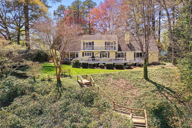back of property with a lawn and a balcony