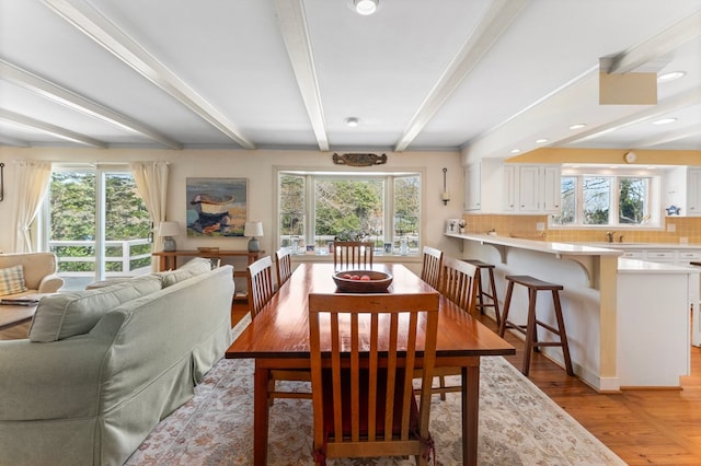 dining area featuring beamed ceiling, plenty of natural light, and light wood-style floors