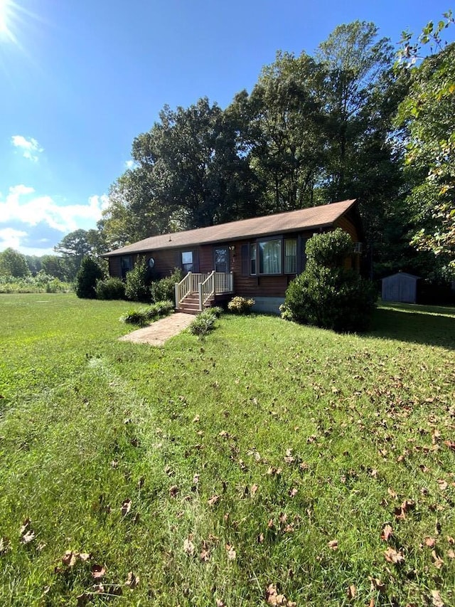 single story home featuring a front yard and a storage shed