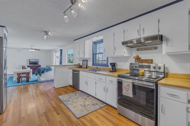 kitchen with stainless steel appliances, sink, white cabinets, and light hardwood / wood-style floors