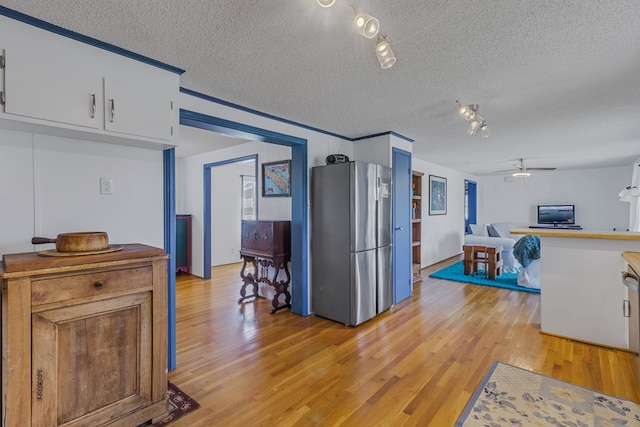 kitchen featuring white cabinetry, stainless steel fridge, a textured ceiling, and light wood-type flooring