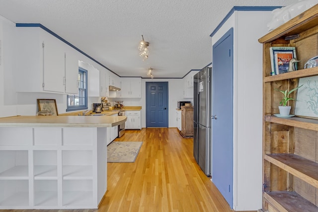 kitchen featuring white cabinetry, stainless steel appliances, kitchen peninsula, and light hardwood / wood-style flooring