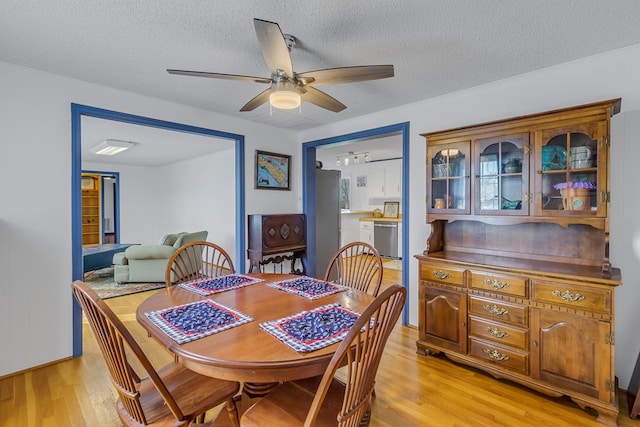 dining space with ceiling fan, a textured ceiling, and light hardwood / wood-style floors