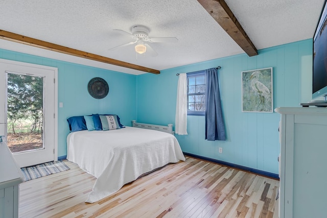 bedroom with ceiling fan, a textured ceiling, beam ceiling, and light hardwood / wood-style flooring