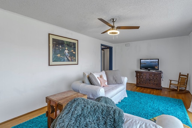 living room with ceiling fan, a textured ceiling, and dark hardwood / wood-style flooring