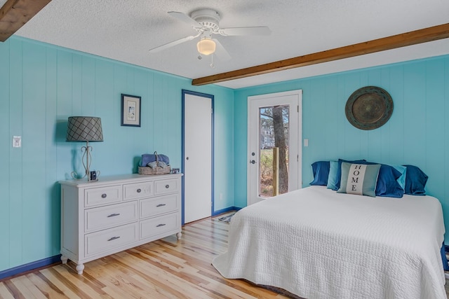 bedroom with beam ceiling, access to outside, a textured ceiling, and light hardwood / wood-style flooring