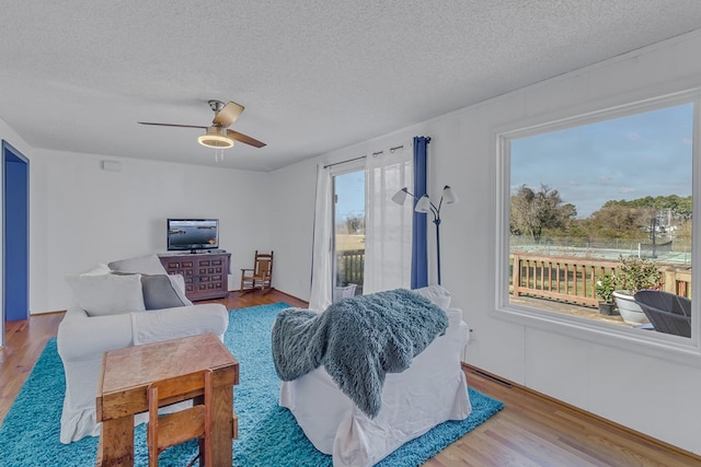 living room with ceiling fan, wood-type flooring, and a textured ceiling