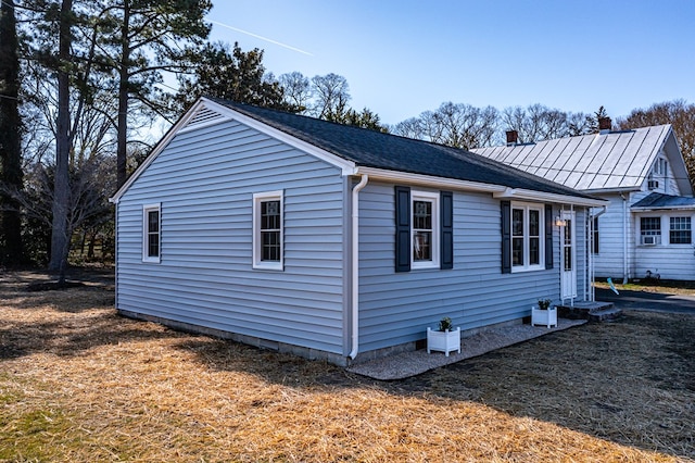 view of home's exterior featuring entry steps and roof with shingles