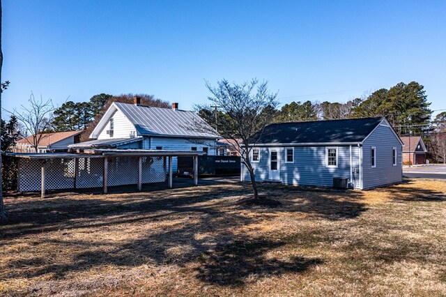 rear view of house featuring cooling unit, fence, and a lawn