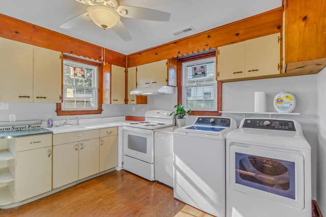 laundry area with visible vents, light wood-type flooring, washer and clothes dryer, a sink, and laundry area