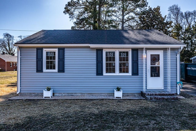 view of front of home featuring a shingled roof and a front yard