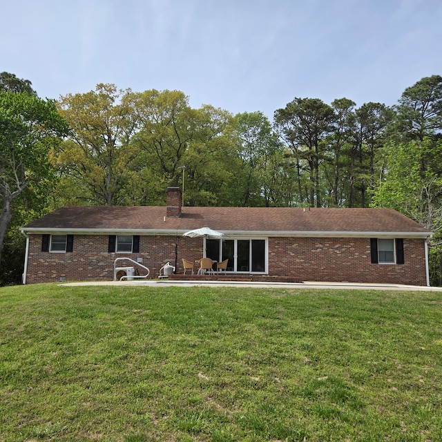 view of front facade with a chimney, brick siding, and a front yard