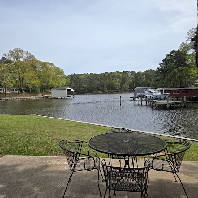 view of patio / terrace with a boat dock, a wooded view, and a water view