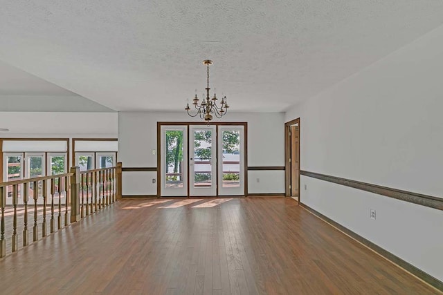 1061 Twiggs Ferry Rd, Hartfield, VA 23071 - unfurnished room with a chandelier, wood finished floors, and a textured ceiling
