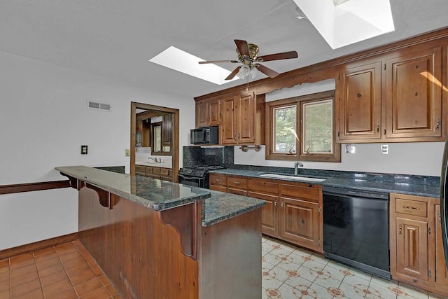1061 Twiggs Ferry Rd, Hartfield, VA 23071 - kitchen with black appliances, a skylight, a kitchen breakfast bar, a ceiling fan, and brown cabinets