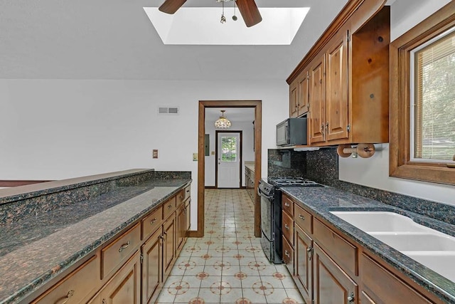 1061 Twiggs Ferry Rd, Hartfield, VA 23071 - kitchen with black appliances, a skylight, a ceiling fan, dark stone counters, and brown cabinets
