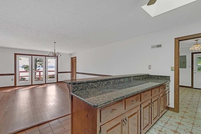 1061 Twiggs Ferry Rd, Hartfield, VA 23071 - kitchen featuring a chandelier, a peninsula, dark stone countertops, a skylight, and a textured ceiling