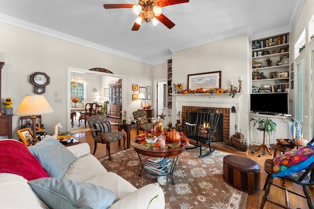 living room featuring a brick fireplace, built in features, ornamental molding, and wood-type flooring