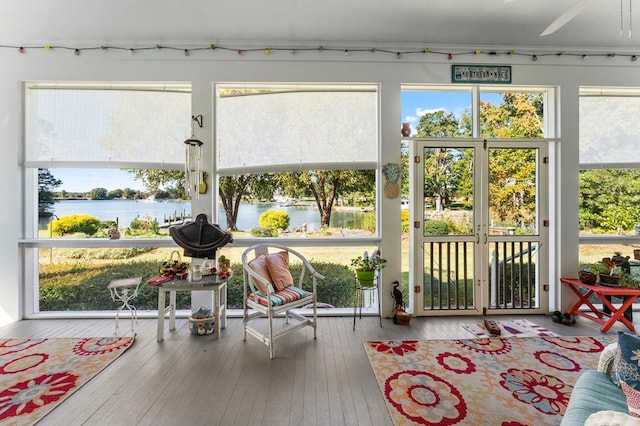 sunroom featuring ceiling fan and a water view