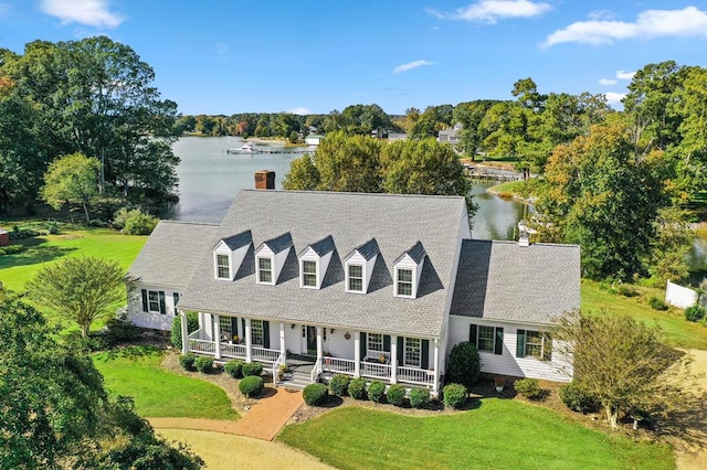 cape cod home featuring covered porch, a water view, and a front lawn