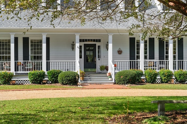 property entrance with a shingled roof, a porch, and a yard